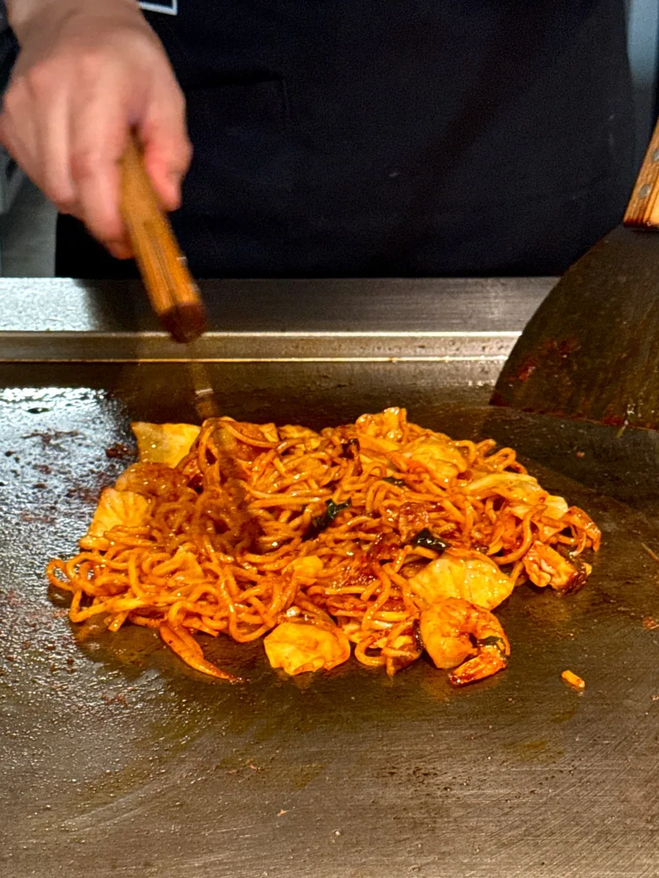 赤いたれで炒められている焼きそばとエビ、キャベツ